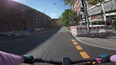 Münih, Almanya 'da bisiklet yolları boyunca POV bisiklet sürüyor. Modern bisiklet altyapısı, güvenli bisiklet yolları, yol işaretleri ve güneşli bahar atmosferi olan bir Avrupa şehrinde sürdürülebilir ulaşım 