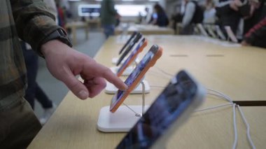 2 Ekim 2025. Münih, Almanya. Portakal rengi iPhone 17 Pro Almanya 'daki Apple Store Münih' te sergileniyor. Adam perakende satış noktasında yeni Apple akıllı telefonunu keşfediyor. Modern cihaz, premium tasarım, son teknoloji.