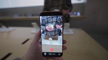 2 Ekim 2025. Münih, Almanya. Apple Store Münih Almanya, kadın yeni iPhone kamerasını test ediyor. Avrupa 'da yenilikçi fotoğraf ve video özellikleri, sancak gemisi akıllı telefon görüntüsü, ön sipariş ve perakende satış gösterisi