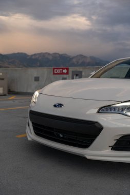 Arka planda dağlar olan bir otoparkın tepesindeki beyaz Subaru BRZ 'nin yakın çekim görüntüsü. Salt Lake City, Utah 'da çekilmiş kaliteli bir fotoğraf.