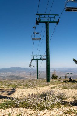 Deer Valley Resort 'taki vadiye bakan bulutsuz güneşli bir günde Kel Dağ' ın tepesinden yeşil bir kayak asansörü. Park City, Utah 'ta çekilmiş kaliteli bir fotoğraf..