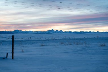 Karlı bir kış gününde güneşin doğuşu sırasında Teton Dağları 'nın çarpıcı manzarası. Ashton, Idaho 'dan Grand Teton Ulusal Parkı' nın kaliteli bir fotoğrafı..