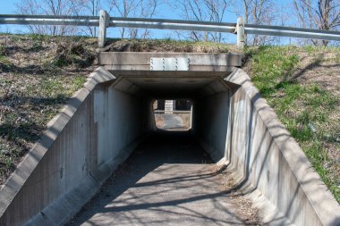 İlkbaharın başlarında bir korkuluk ve çıplak ağaçlar tarafından çerçevelenmiş bir yaya tüneli bir yolun altından geçer. Sahne huzur ve yalnızlığı çağrıştırıyor, kıştan bahara geçişi gösteriyor..