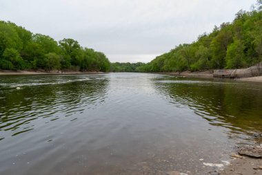 Minnesota, Minnehaha Şelalesi yakınlarındaki Mississippi Nehri manzaralı. Sakin sular ve yemyeşil manzara, nehirlerin doğal güzelliğini gösteren sakin ve resimsel bir ortam yaratır..