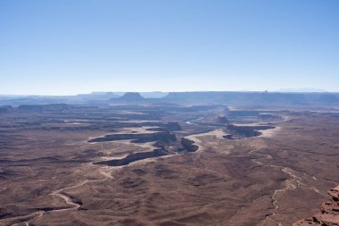 Canyonlands Ulusal Parkı 'ndaki Green River Overlook' dan nefes kesici bir manzara. Panoramik manzara, engebeli, renkli manzaranın ortasındaki kıvrımlı Yeşil Nehir 'i gösteriyor. Parkların doğal güzelliğini vurguluyor..