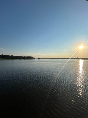 Texas 'taki Cedar Creek Rezervuarı üzerinde sakin sulara yansıyan canlı renklerle güzel bir günbatımı. Bu sakin sahne, bu popüler açık hava mekanının huzur dolu güzelliğini vurguluyor..