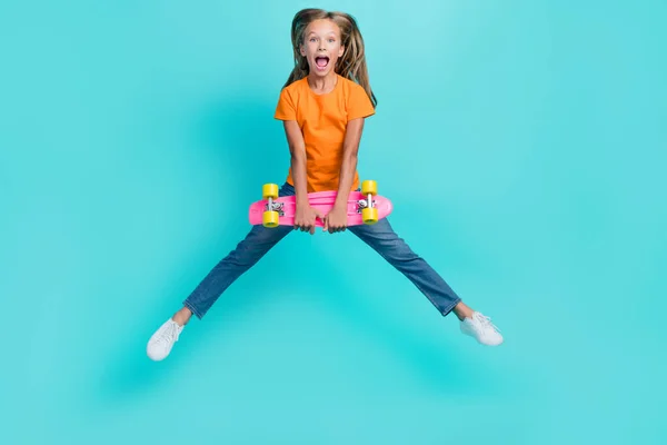 かなり興奮した小さな子供の完全な長さの写真ドレスオレンジ色のTシャツジャンプ高保持スケートボード孤立した電話色の背景 — ストック写真