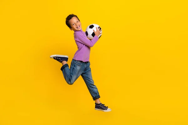 フルボディポートレートの励起スポーティな子供ジャンプ手ホールドボール絶縁上の黄色の背景 — ストック写真