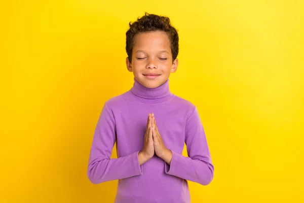 stock image Photo portrait of charming little boy closed eyes hands pray gesture make wish wear trendy violet look isolated on yellow color background.