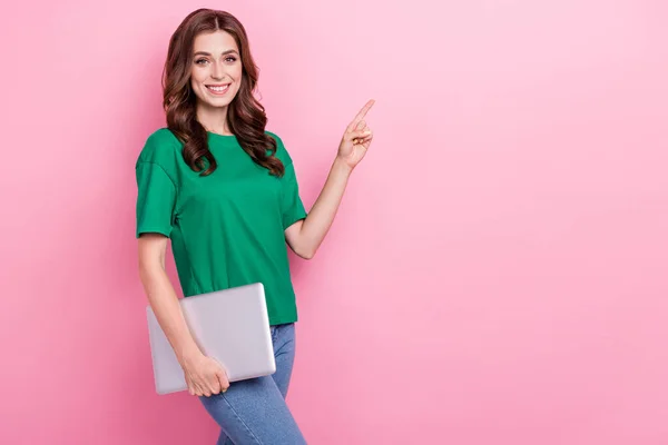 波状の髪型をした肯定的な素敵な女の子の写真緑のTシャツはピンクの色の背景に隔離された空のスペースを演出ノートパソコンを保持 — ストック写真