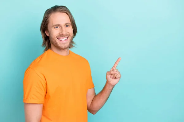 照片上可爱的男人穿着橙色的T恤 手指指向空旷的空旷的空间 孤立的茶色背景 — 图库照片