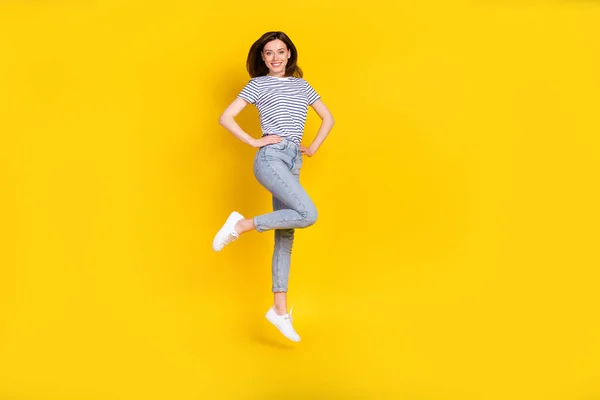 손으로 점프하는 귀여운 아가씨의 사진은 노란색 배경에 고립된 줄무늬 — 스톡 사진