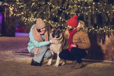 Photo of funny charming wife husband walking cuddling small best puppy friend smiling outside city fair street. clipart