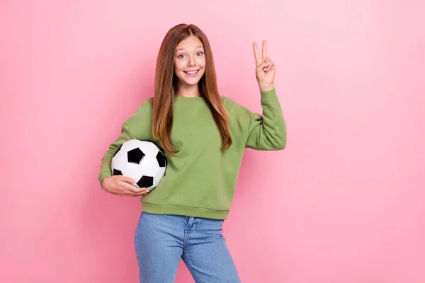 写真の甘い陽気女子高生着用緑のトレーナー遊びサッカーショーV Sign孤立したピンク色の背景 — ストック写真