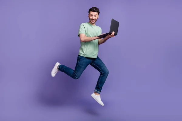 Full length photo of positive man buy modern quality gadget device apple macbook move go empty space isolated on purple color background.