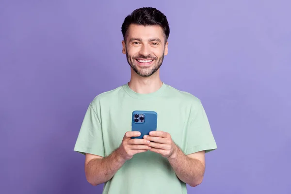 迷人的年轻男子手持装置的照片肖像灿烂的微笑穿着时髦的灰色衣服 与紫色背景隔离 — 图库照片