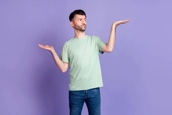 不确定的男人举起双臂不同低价产品相对于紫色背景的天平空隙 — 图库照片