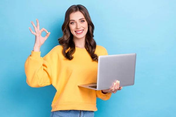 若い愛らしい笑顔の写真かわいい女の子は黄色のセーターを着用ホールドコンピュータを示すキーサインおもちゃの笑顔は青の色の背景に隔離されたアプリをお勧めします — ストック写真