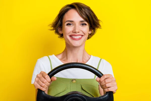 可爱的年轻女子手握方向盘的照片 买新车的车主穿着时髦的卡其布 看上去与黄色背景隔离 — 图库照片