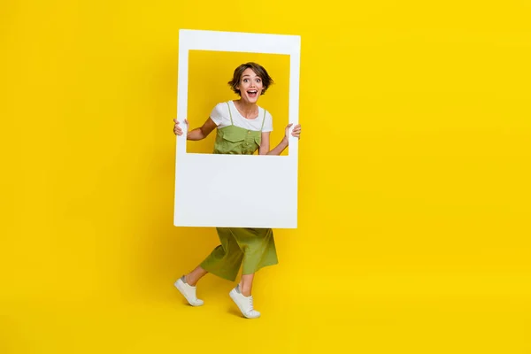 フルボディサイズの写真のかなりかわいい女の子身に着けているカーキ服ホールド紙ホワイトウィンドウ励起撮影レポスト隔離された黄色の色の背景 — ストック写真