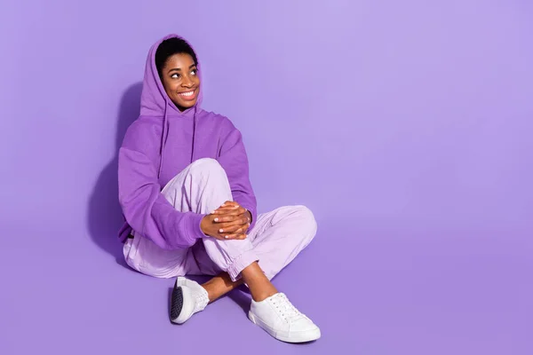 stock image Full size photo of funny young lady sit look promo wear hoodie trousers footwear isolated on purple color background.