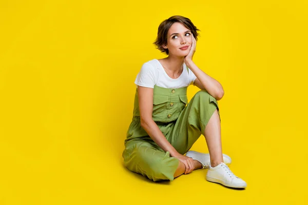 stock image Full body photo of nice young lady sit floor look interested empty space dressed stylish khaki outfit isolated on yellow color background.