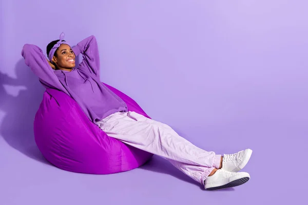 Photo of nice attractive dreamy transgender enjoy beanbag sleep wear headband hoodie isolated purple color background.