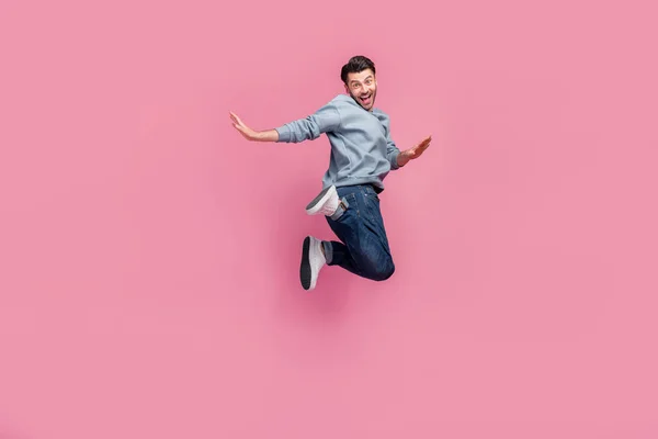 若いです魅力的なハンサムな子供っぽい男遊び心のある学生ジャンプ空気足アップクレイジー新しいショッピングモール割引ピンク色の背景に孤立 — ストック写真