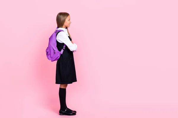 全身上下都是可爱的小学生小女孩穿着校服买新背包购物的照片 看上去空空荡荡的 用粉色背景隔开的空间广告 — 图库照片
