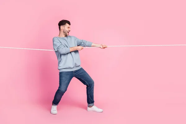 Profile side full body photo of determined guy pulling string winning isolated on pastel color background.