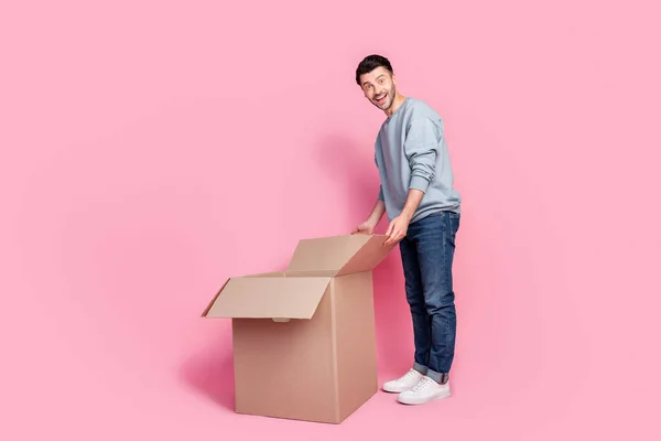 フルサイズ写真のハンサムな若い男励起オープニング大きな小包空のスペース服トレンディーな青の外観隔離されたピンク色の背景 — ストック写真
