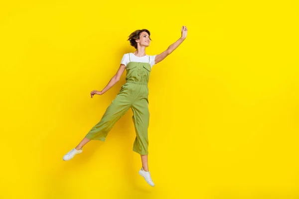 フルボディ写真の若いかわいい女性の夏服着用全体ジャンプエアホールド指興味のある空のスペースに黄色の色の背景に隔離 — ストック写真