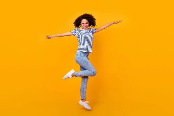 全身上下都是精力充沛 快乐的女孩跳起来的照片 有很好的心情在黄色的背景下与外界隔绝 — 图库照片