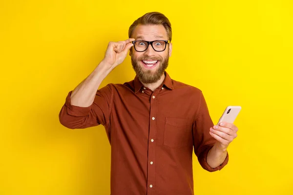 男式胡子 勃艮第衬衫 令人印象深刻的狂喜男子的画像 手持黄色背景的智能手机触觉眼镜 — 图库照片