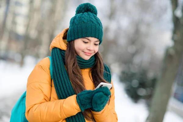 stock image Portrait of attractive focused girl wearing warm outfit using device gadget watching video wintertime snowy weather outdoors.