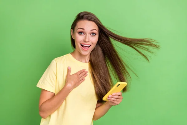 ストレートヘアスタイルでかわいい可愛い可愛い肯定的な女の子の写真は 黄色のTシャツを着てちょうど緑の色の背景に素晴らしいニュースを読む — ストック写真
