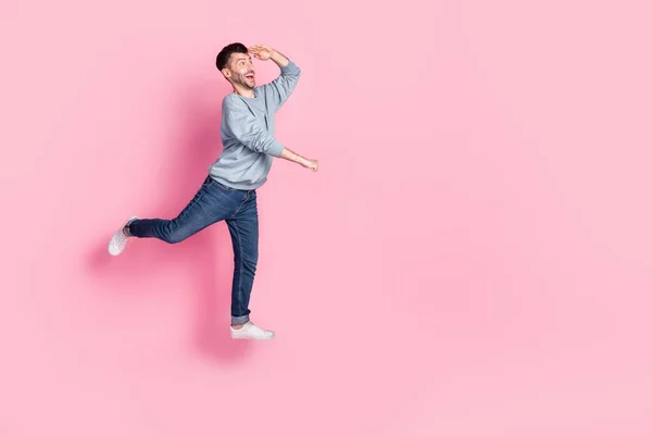 魅力的な若い男の完全な長さの写真ジャンププッシュショッピングカート興奮した外観のための服スタイリッシュな青の外観ピンク色の背景に隔離 — ストック写真