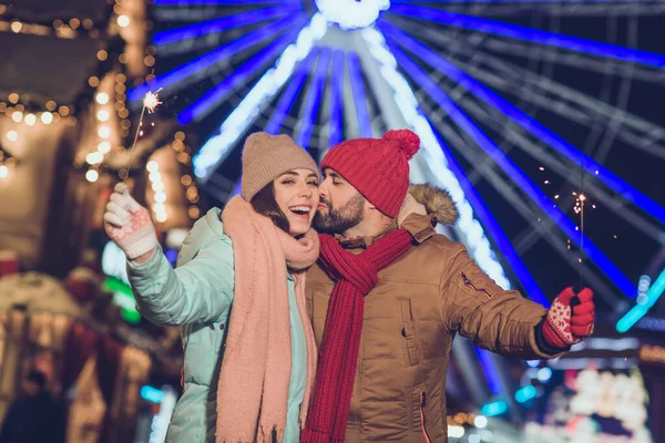 Photo of two lovely idyllic people hold bengal fire lights stick kiss cheek x-mas evening miracle magic outside.