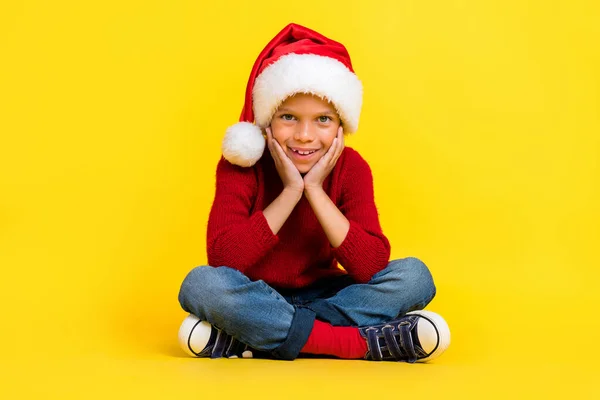 Full size photo of cute small boy sit floor enjoy christmas new year dressed stylish red knitted outfit isolated on yellow color background.
