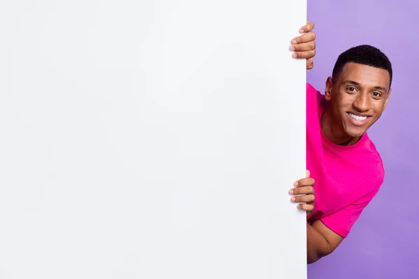 时尚酷男穿着时髦的粉色衣服手拿着空旷的空间展示紫色背景下的大海报 — 图库照片