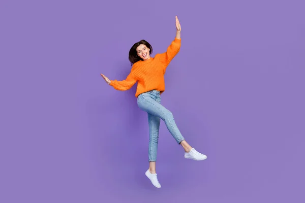 美しい若い女性のダンスジャンプのフルサイズの写真は楽しい着用トレンディーなオレンジ色のニットウェアの服は 紫色の背景に隔離されている — ストック写真