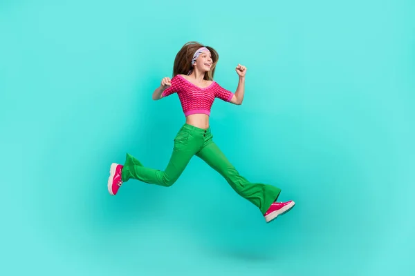 stock image Full length photo of excited cool school girl dressed pink crop top flared pants jumping high running isolated teal color background.