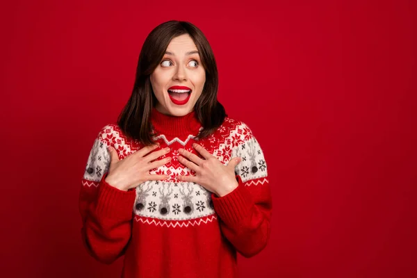 Photo of impressed ecstatic girl straight hairstyle dressed red sweater look empty space palms on chest isolated on red color background.