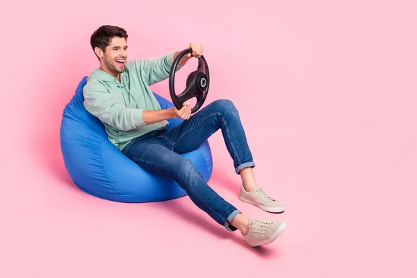クレイジー男の子座って椅子のフル長さの写真は楽しいエンターテイメントを持っています新しい自分の車はピンクの色の背景に隔離された空のスペースに乗る旅を楽しむ — ストック写真