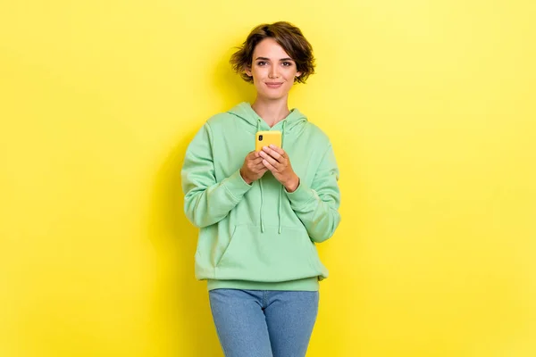 豪華な若い女の子の写真は デバイスのタイプメッセージ読書ニュースは黄色の色の背景に隔離された流行の緑の服を身に着けている — ストック写真