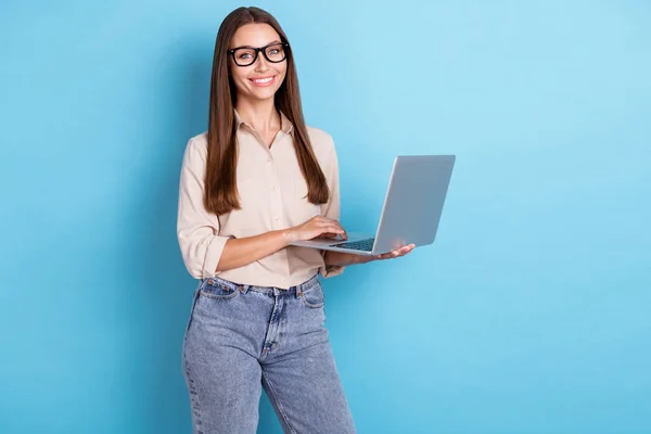照片上漂亮华丽自信的女士身穿米色衬衫牛仔裤 手持笔记本电脑 准备开一个蓝色背景的会 — 图库照片