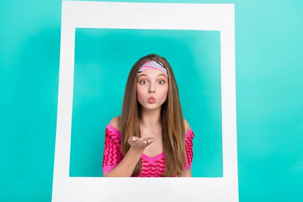 Photo of pretty adorable school girl dressed pink crop top sending kiss photographing white paper frame isolated teal color background.