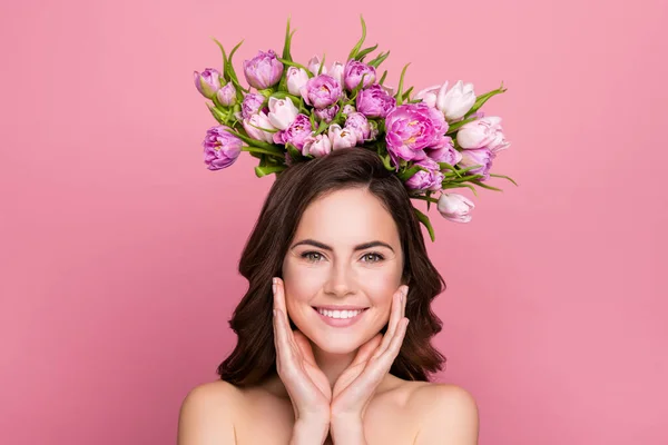 Photo of cute funny young nude lady wear nothing holding tulips bloom crown arms cheeks isolated pink color background.
