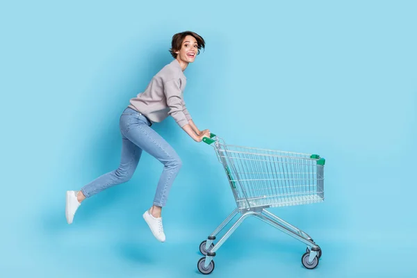 フルボディプロフィール写真の短い毛若い女性が実行ショッピングシャツジーンズの靴隔離された青の色の背景 — ストック写真