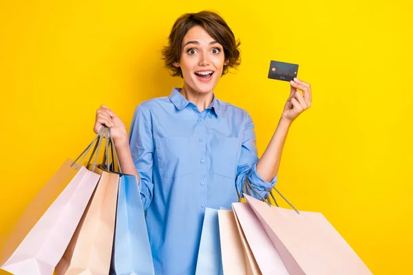 かなり興奮した女性の写真青シャツを保持買い物客銀行カード絶縁黄色の背景 — ストック写真
